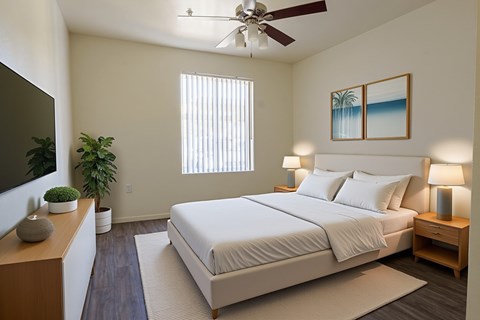 A bedroom with a large bed, a ceiling fan, and a painting of a beach scene on the wall.