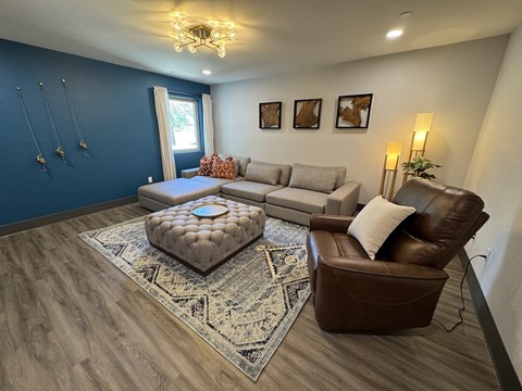 A living room with a brown leather chair and a grey ottoman.