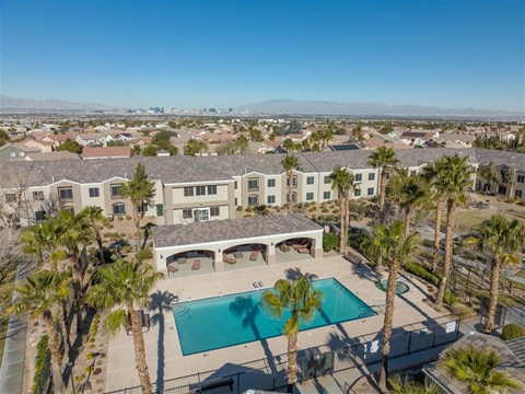 A large house with a pool surrounded by palm trees.