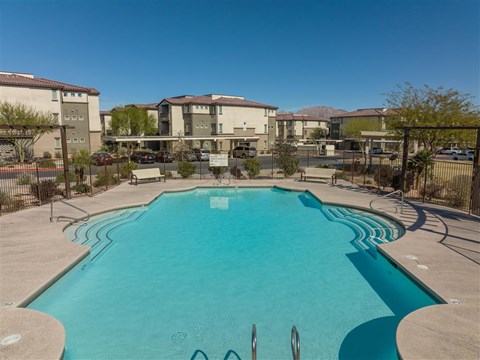 A swimming pool in a residential area with apartment buildings in the background.