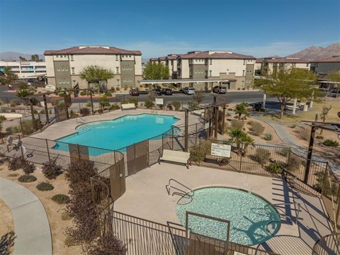 A pool surrounded by a fence and a sign in front of apartment buildings.