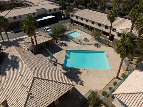 A swimming pool surrounded by palm trees and apartment buildings.