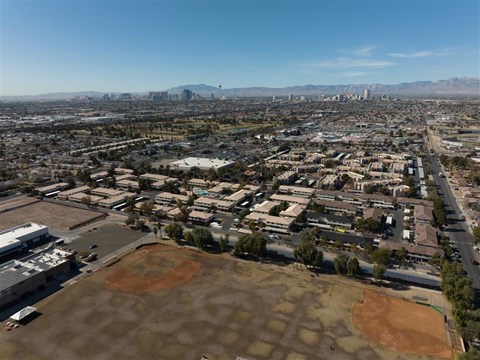 A cityscape with buildings and a baseball field in the foreground.