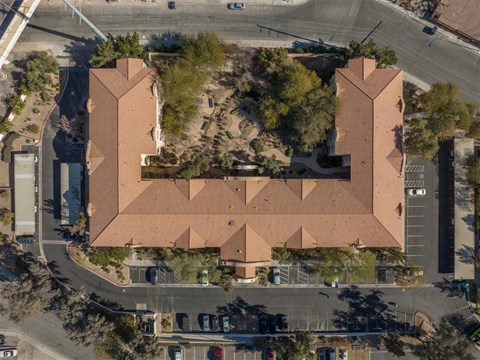 An aerial view of a building with a red roof and a parking lot in front.