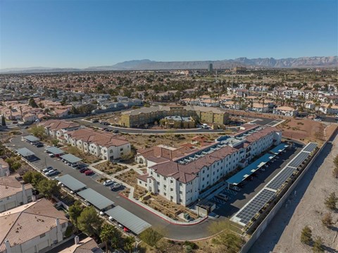 A large white building with a red roof is surrounded by a parking lot.