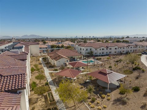 A view of a housing complex with a swimming pool and a mountain range in the background.