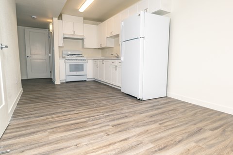 A kitchen with white appliances and wooden floors.