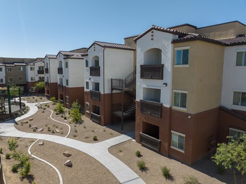 Apartment complex with a pathway and landscaping.