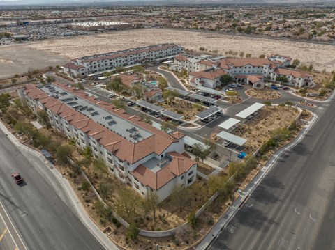 A large apartment complex is surrounded by a parking lot and a road.