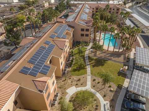 A building with solar panels on the roof and a pool in the courtyard.