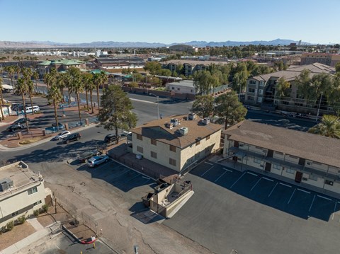 A parking lot with a building in the middle and palm trees around.