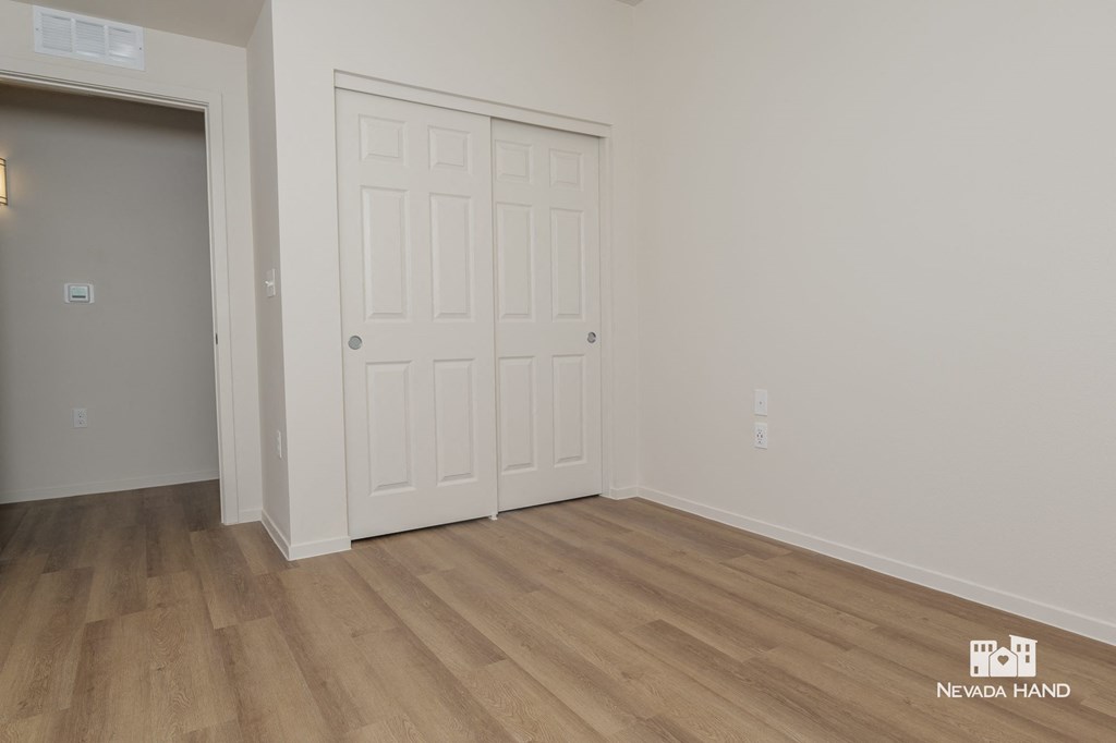the living room of a house with a white door and wooden floors