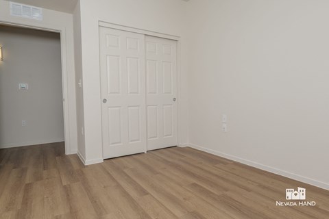 the living room of a house with a white door and wooden floors