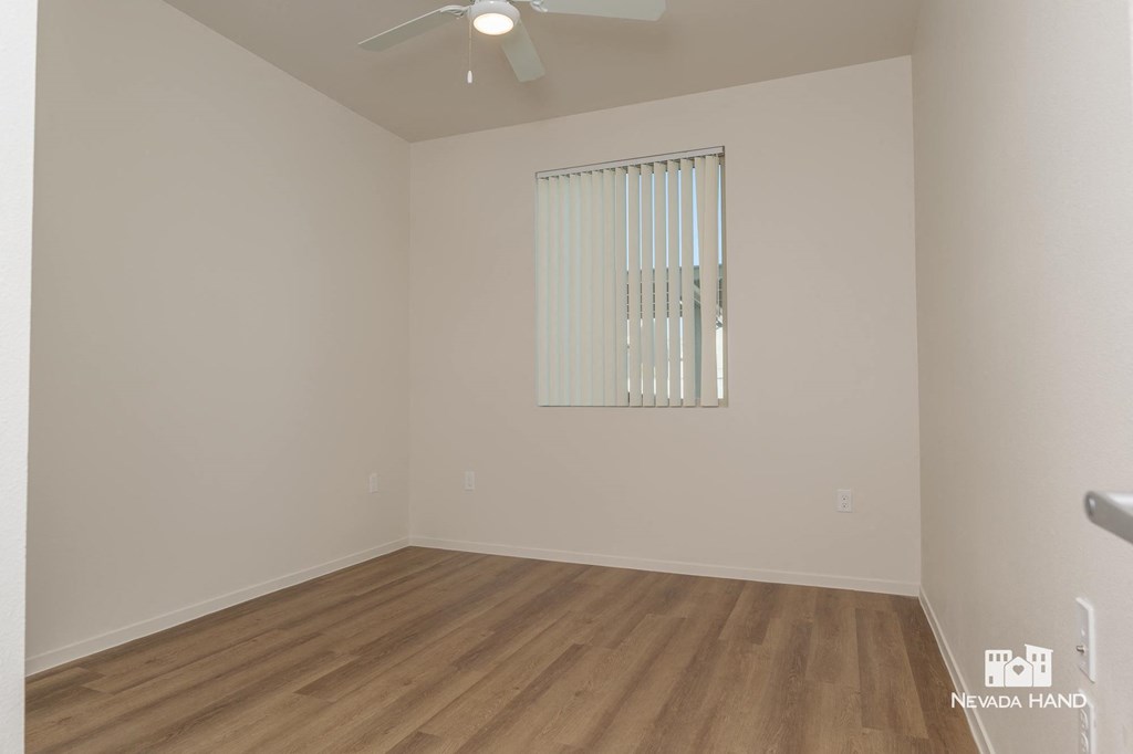 a bedroom with white walls and wood flooring and a window