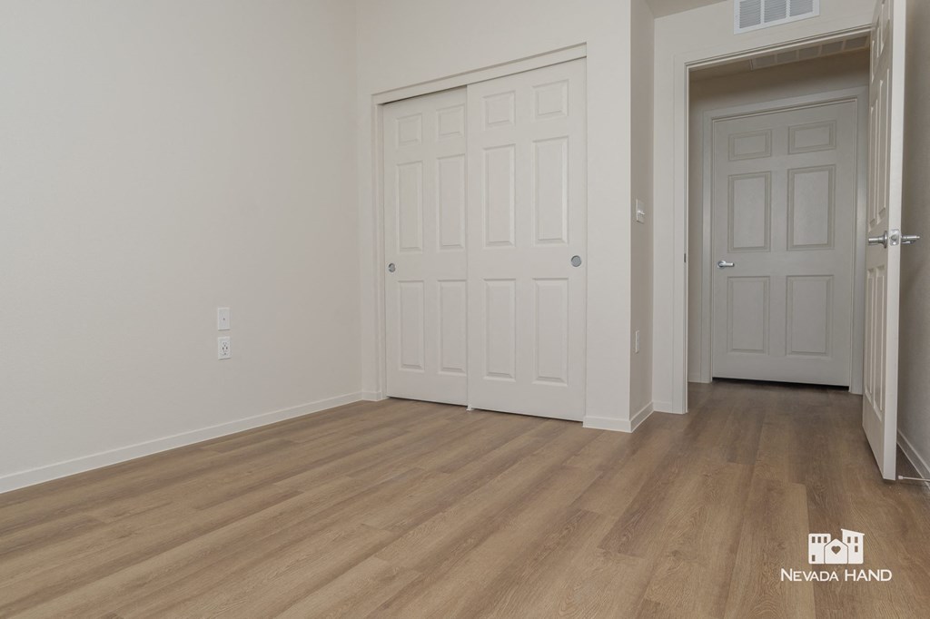 the living room of a house with white walls and wooden floors