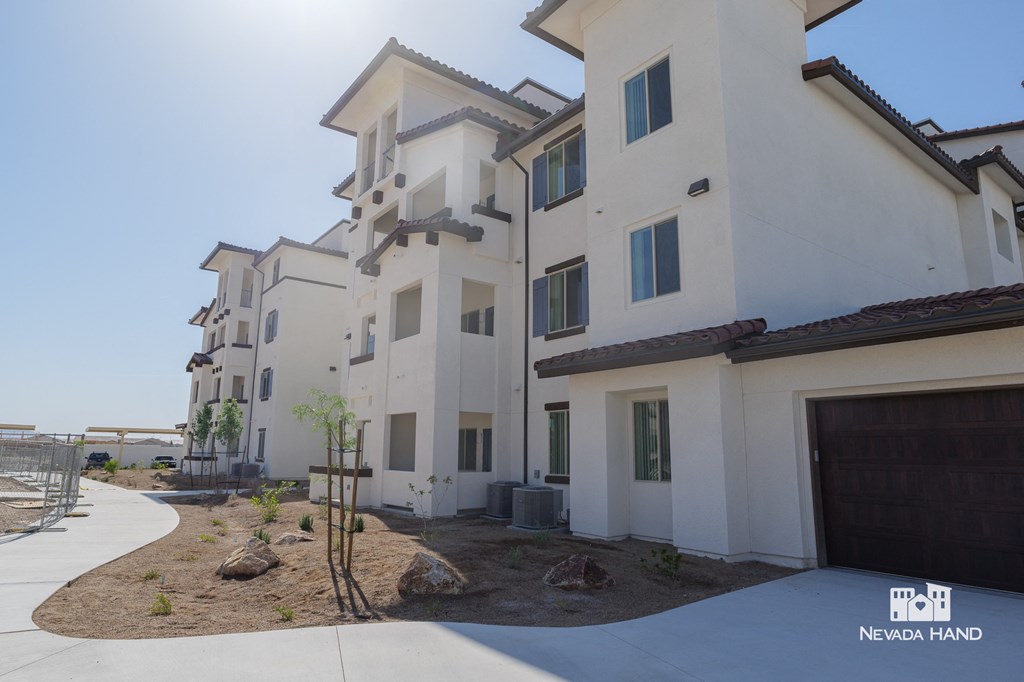 a group of white apartment buildings with a sidewalk and a garage
