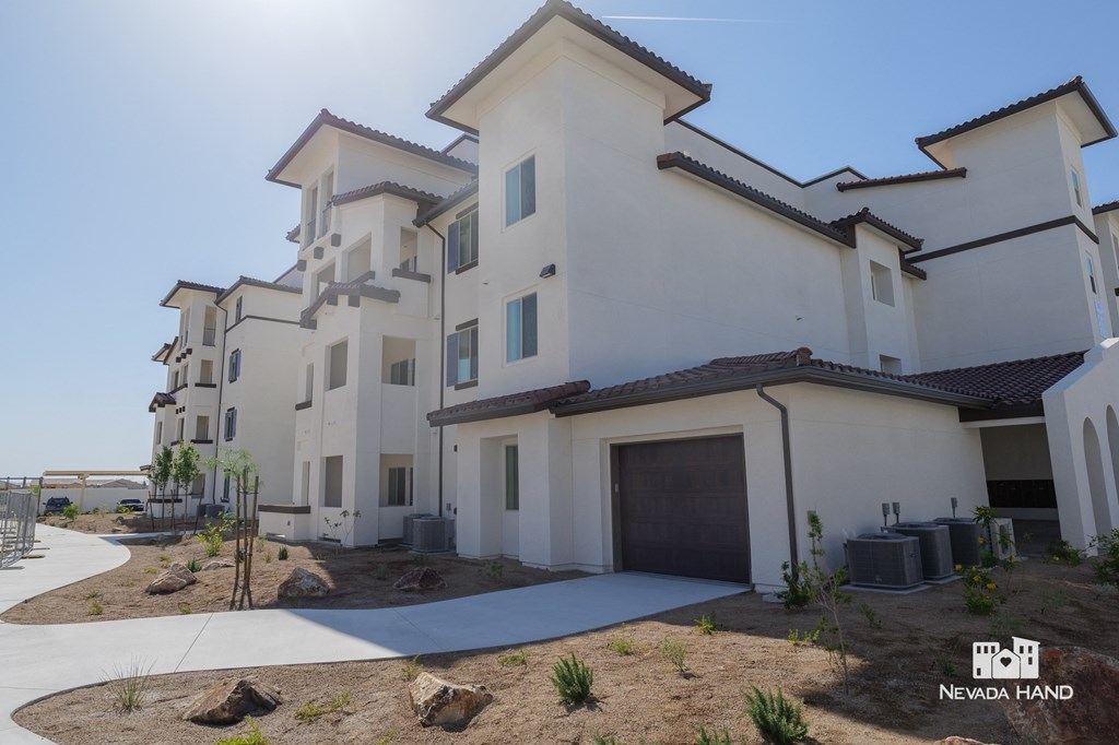 a group of white buildings with a driveway and a garage door