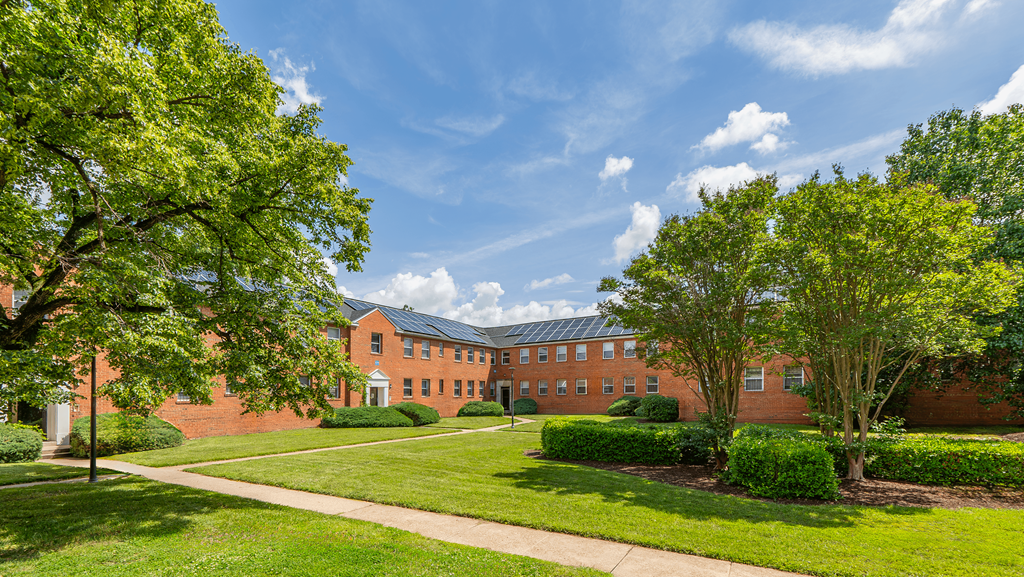A large red brick building with a green lawn in front at Eagles Crossing Apartments, Washington, Washington DC