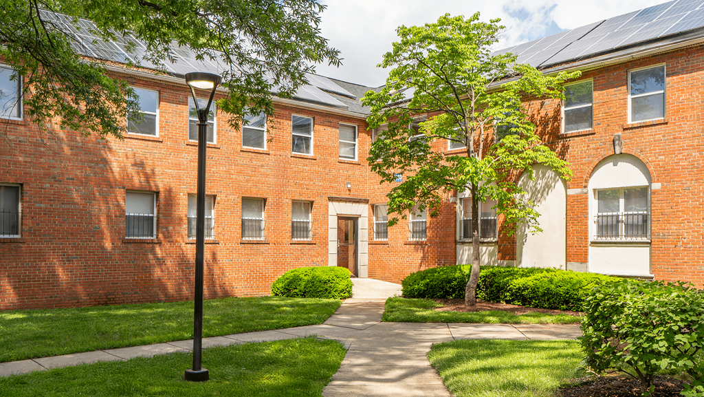 A red brick building with a tree in front at Eagles Crossing Apartments, Washington DC, 20032