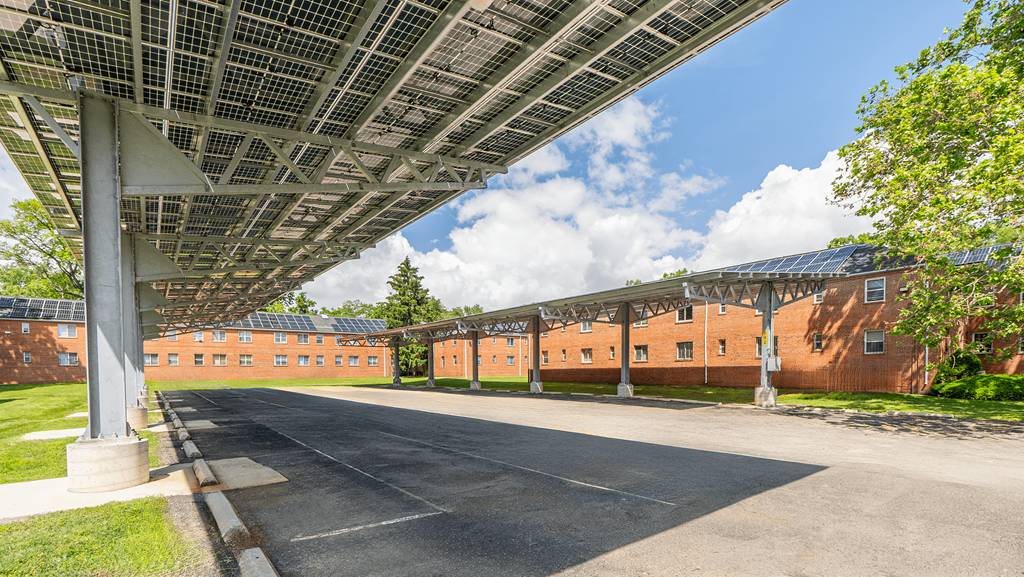 A long building with a metal roof and a parking lot in front at Eagles Crossing Apartments, Washington, DC, 20032