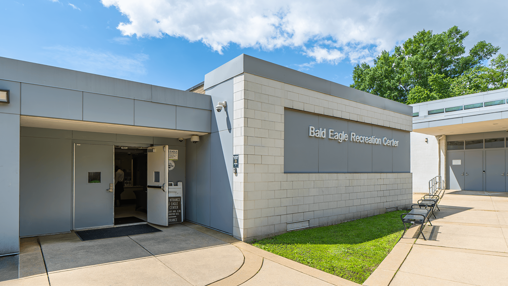 The Bald Eagle Reception Center is a modern building with a white exterior and a glass door at Eagles Crossing Apartments, Washington