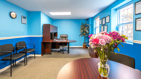 A conference room with a table, chairs, and a vase of flowers.