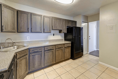 A kitchen with wooden cabinets and a black refrigerator.