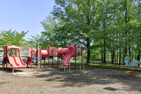 A playground with red slides and a white slide.
