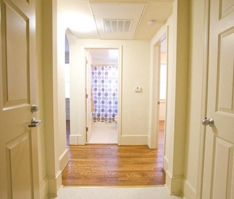 A hallway with white doors and a wooden floor.