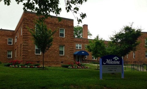 A brick building with a sign that says Milestone in front of it.