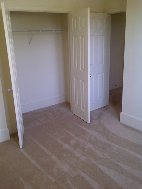 A room with a carpeted floor and two white doors.