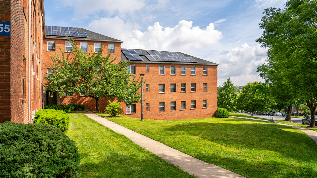 A red brick building with a black roof and solar panels on the roof.