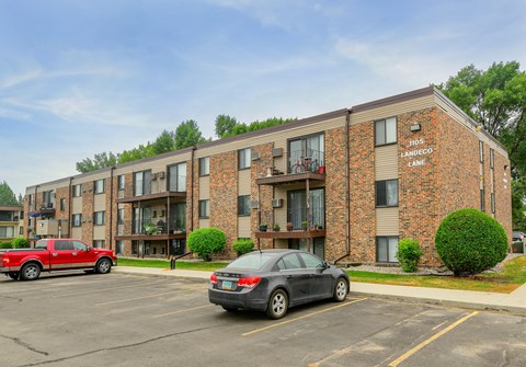 A red truck is parked in front of a brick apartment building.
