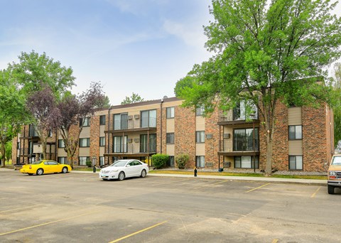 A yellow car is parked in front of a brick building.