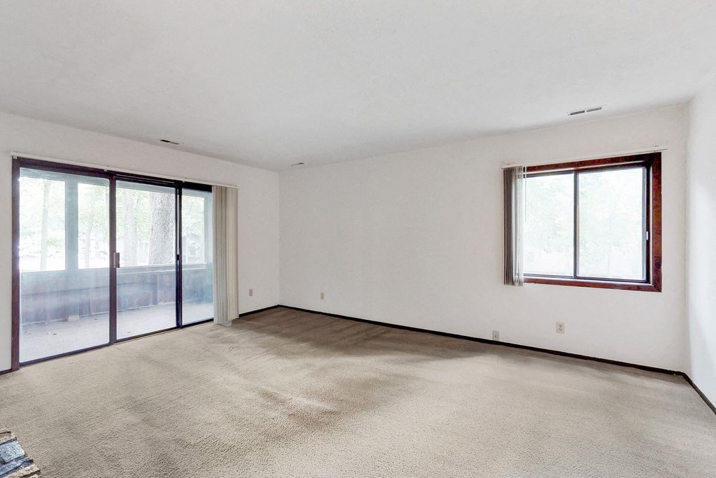 an empty living room with sliding glass doors to a balcony