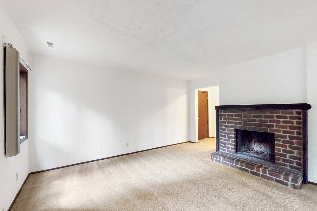 a living room with a brick fireplace and white walls