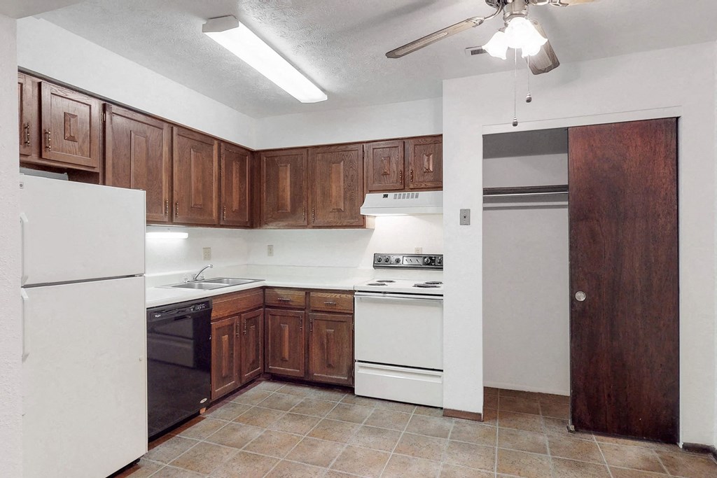 an empty kitchen with white appliances and wooden cabinets