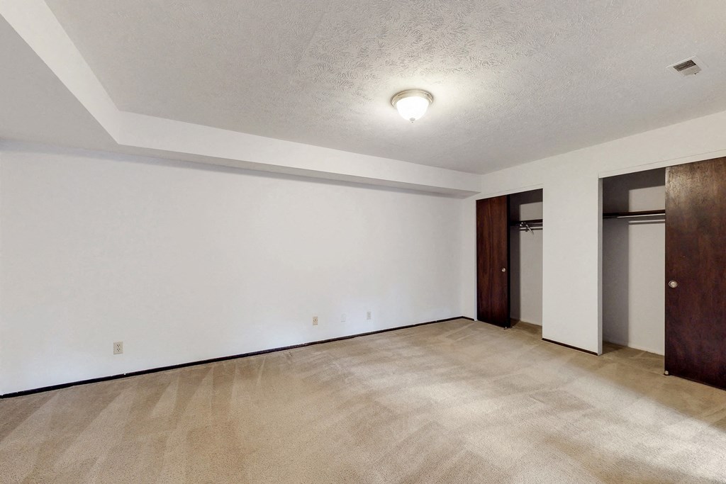 an empty living room with white walls and a door to a closet