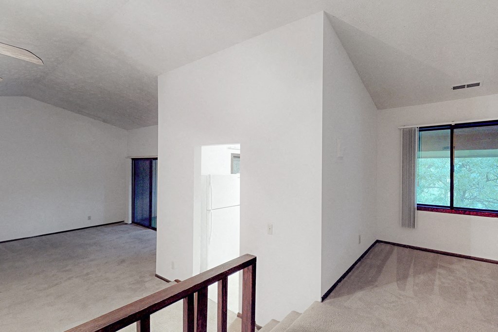 an empty living room with a refrigerator in the middle of it