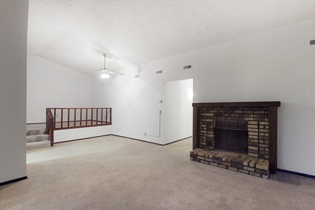 an empty living room with a fireplace and a staircase