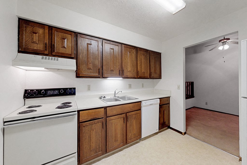 an empty kitchen with white appliances and wooden cabinets