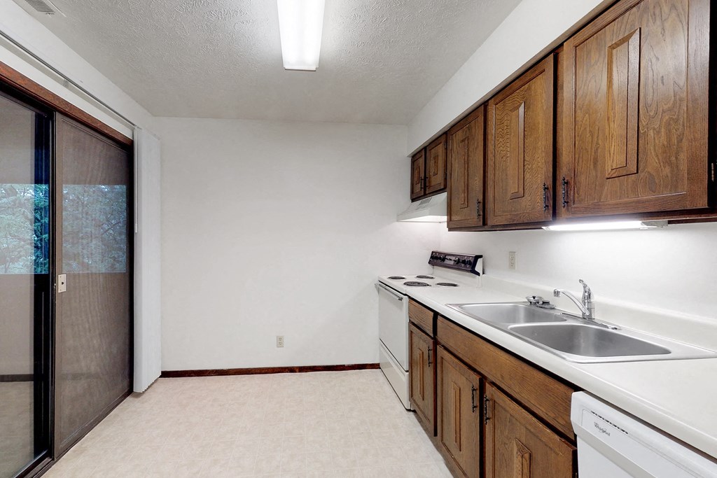 an empty kitchen with white appliances and wooden cabinets