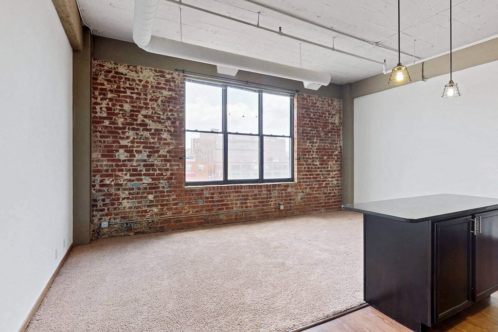 an empty room with a brick wall and a window