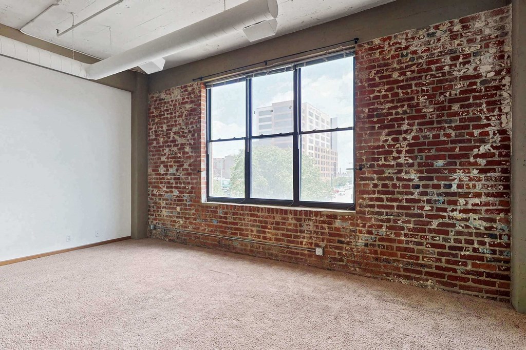 an empty room with a brick wall and a large window