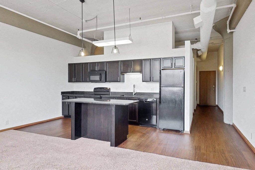 an empty kitchen with an island and stainless steel appliances