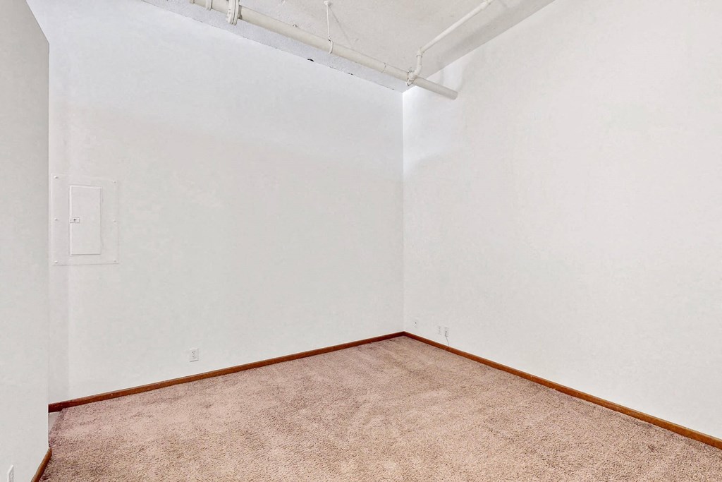 a room with a carpet and a white wall and a door