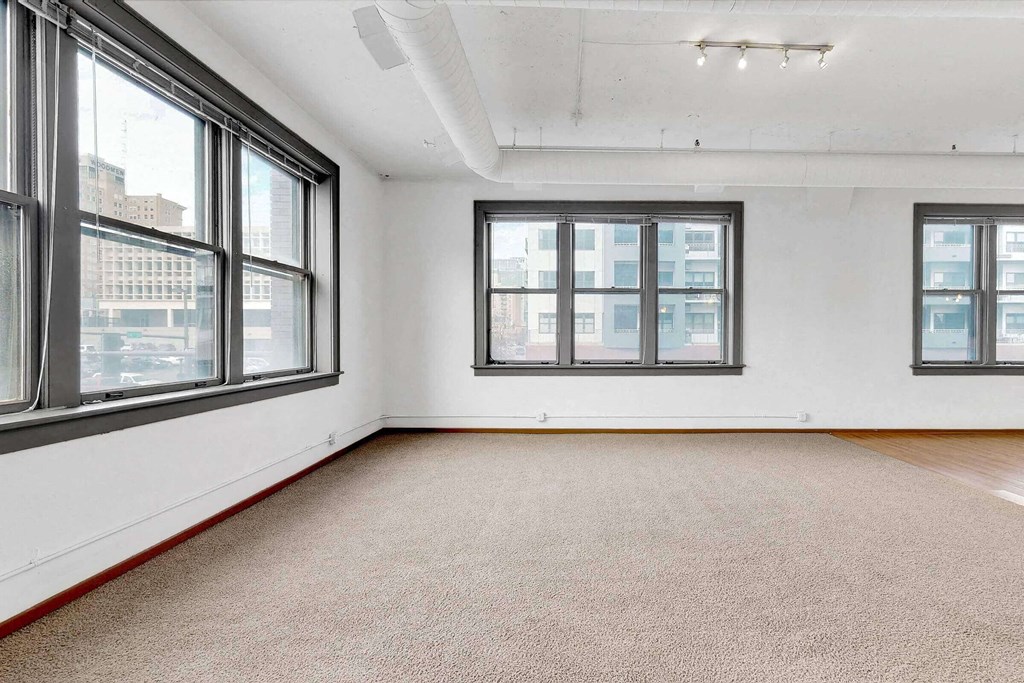 an empty room with three windows and a rug