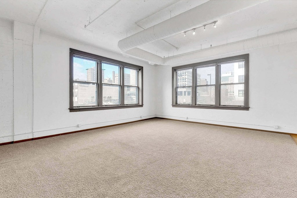 an empty room with three windows and a carpeted floor