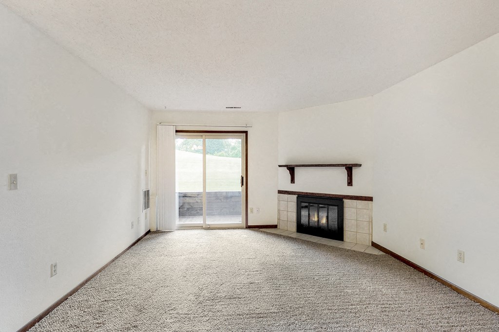 an empty living room with a fireplace and a sliding glass door