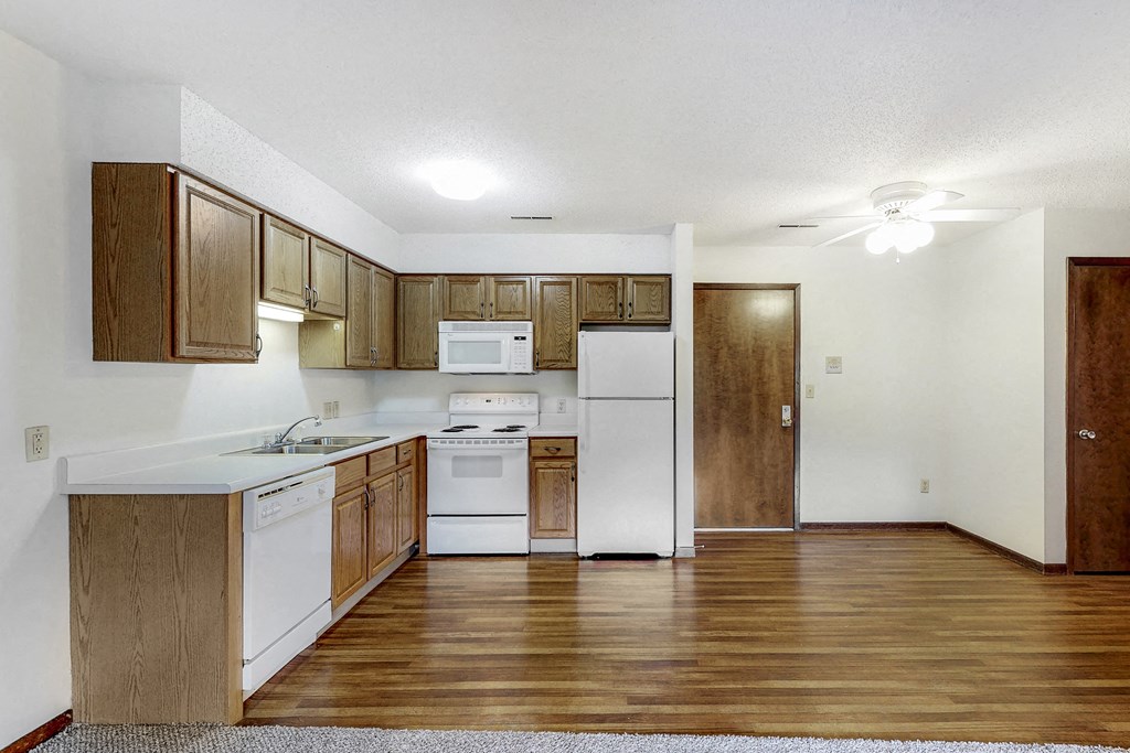 an empty kitchen with wood flooring and white appliances